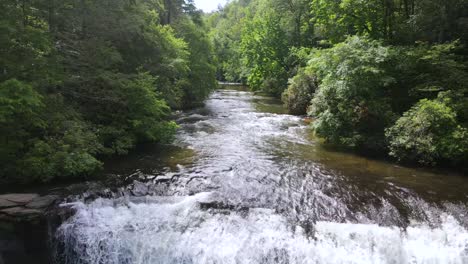 Una-Excelente-Toma-Aérea-De-Un-Río-Que-Desemboca-En-Una-Cascada-En-Carolina-Del-Norte