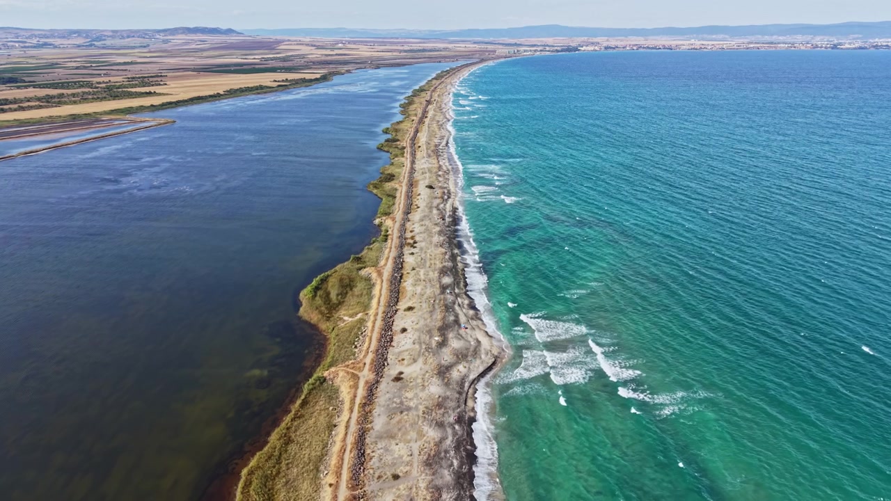 Vista costiera di una lunga striscia di terra che separa due specchi d'acqua durante una luminosa giornata