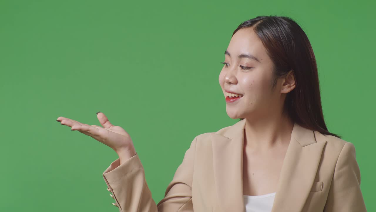 緑のスクリーンに立っている間開いた手の手のひらを示すアジアのビジネス女性のクローズアップ