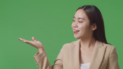 close up of asian business woman showing open hand palm while standing in the green screen