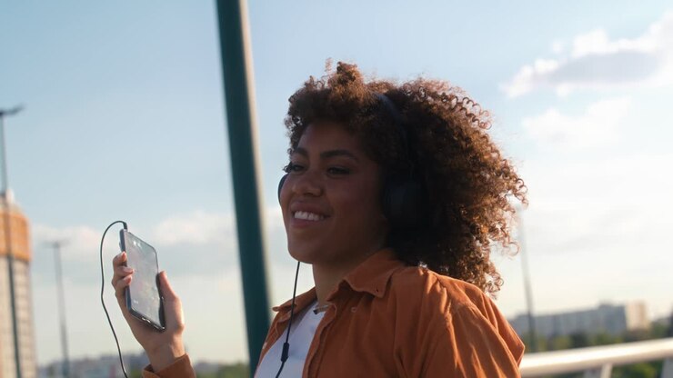 Black woman wearing headphones and dancing on the bridge.