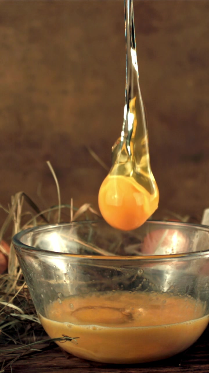 Fresh Egg Yolk and White Separating into a Glass Bowl in Slow Motion