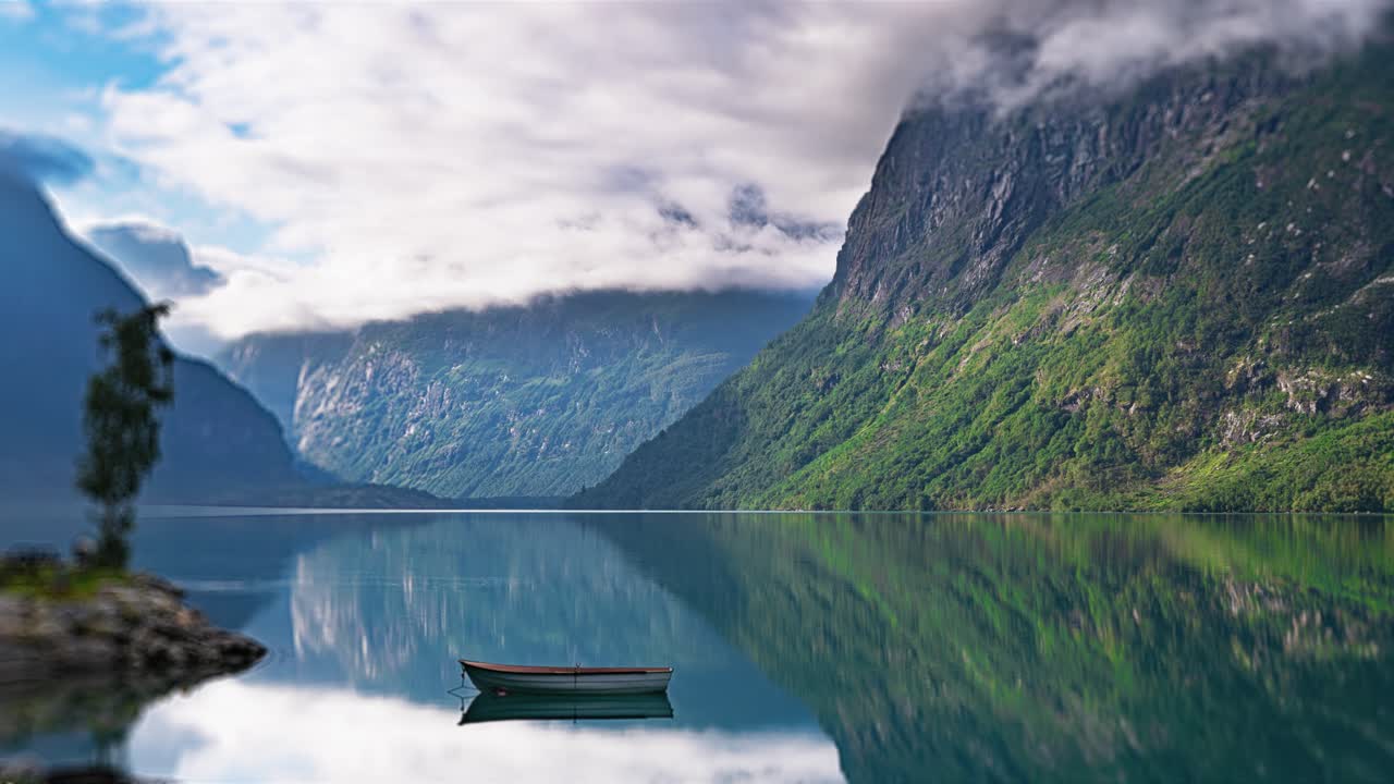 un tranquilo vídeo en lapso de tiempo de las aguas como espejo del lago loen y las montañas cubiertas de bosques