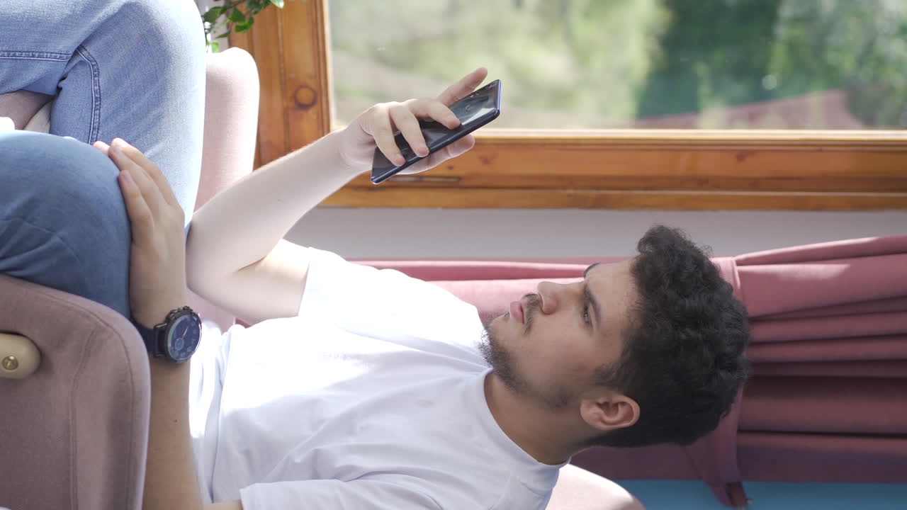 전화로 문자 메시지를 보내는 남자가 여자친구와 헤어지는 수직 비디오입니다.