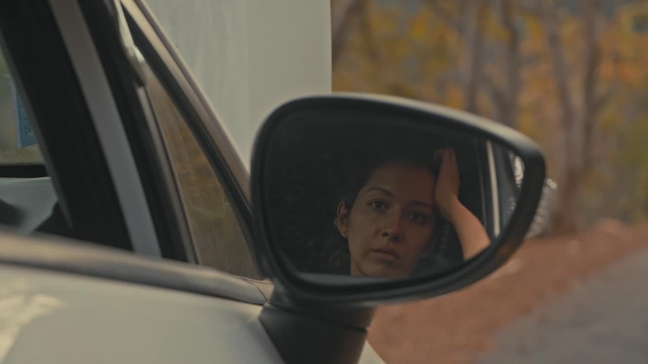 Woman looking in car side mirror