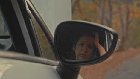 woman looking in car side mirror