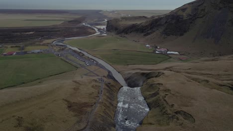 Eine-Drohne-Folgt-Dem-Fluss-Des-Skógafoss-wasserfalls-über-Die-Klippenkante
