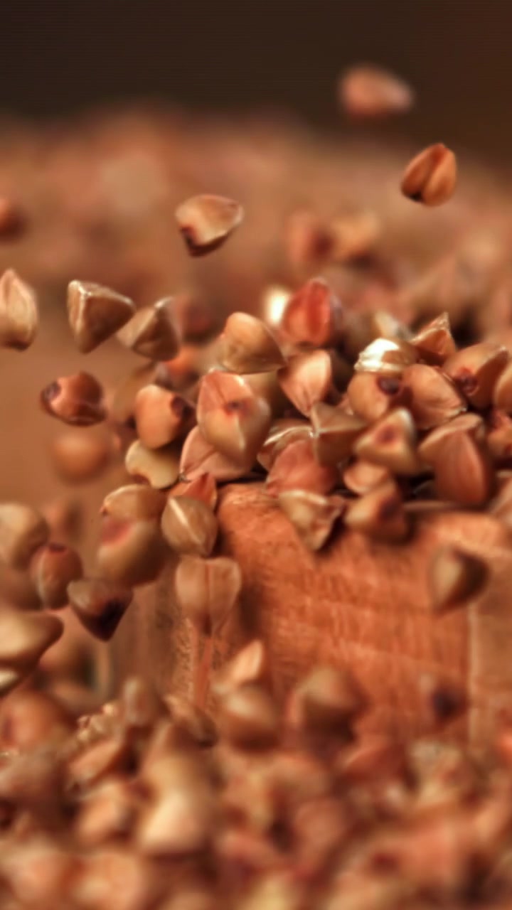 Raw Buckwheat Grains Falling in Slow Motion onto a Wooden Surface
