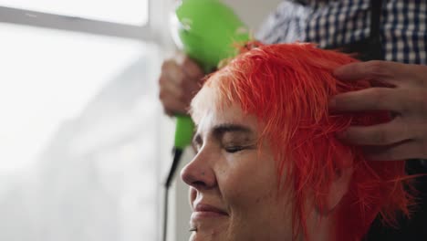 side view woman having her hair dry by a hairdresser