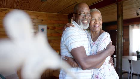 Glückliches-älteres-Afroamerikanisches-Paar,-Das-Sich-Zu-Hause-Umarmt-Und-Aus-Dem-Fenster-Schaut,-Zeitlupe