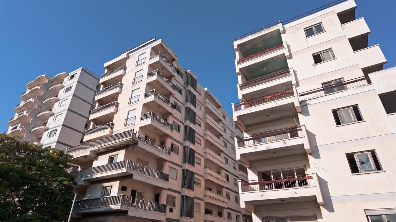 Abandoned apartment buildings in Varosha with clear blue sky and surrounding greenery