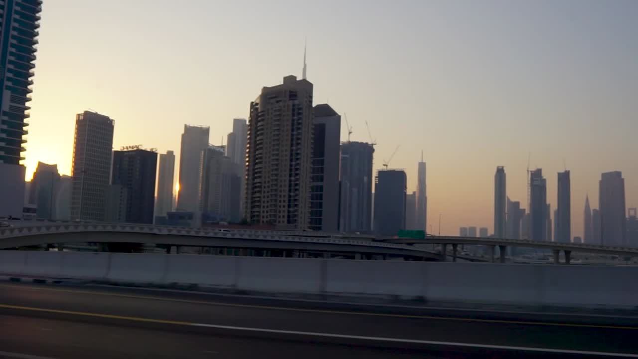 conduciendo por las carreteras de dubai al atardecer con el horizonte retroiluminado