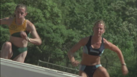 a group of women run and jump over hurdles