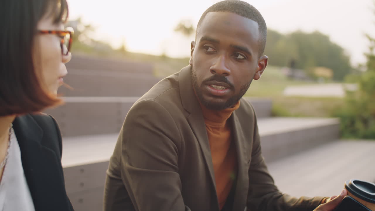 hombre de negocios afroamericano hablando con un colega asiático al aire libre