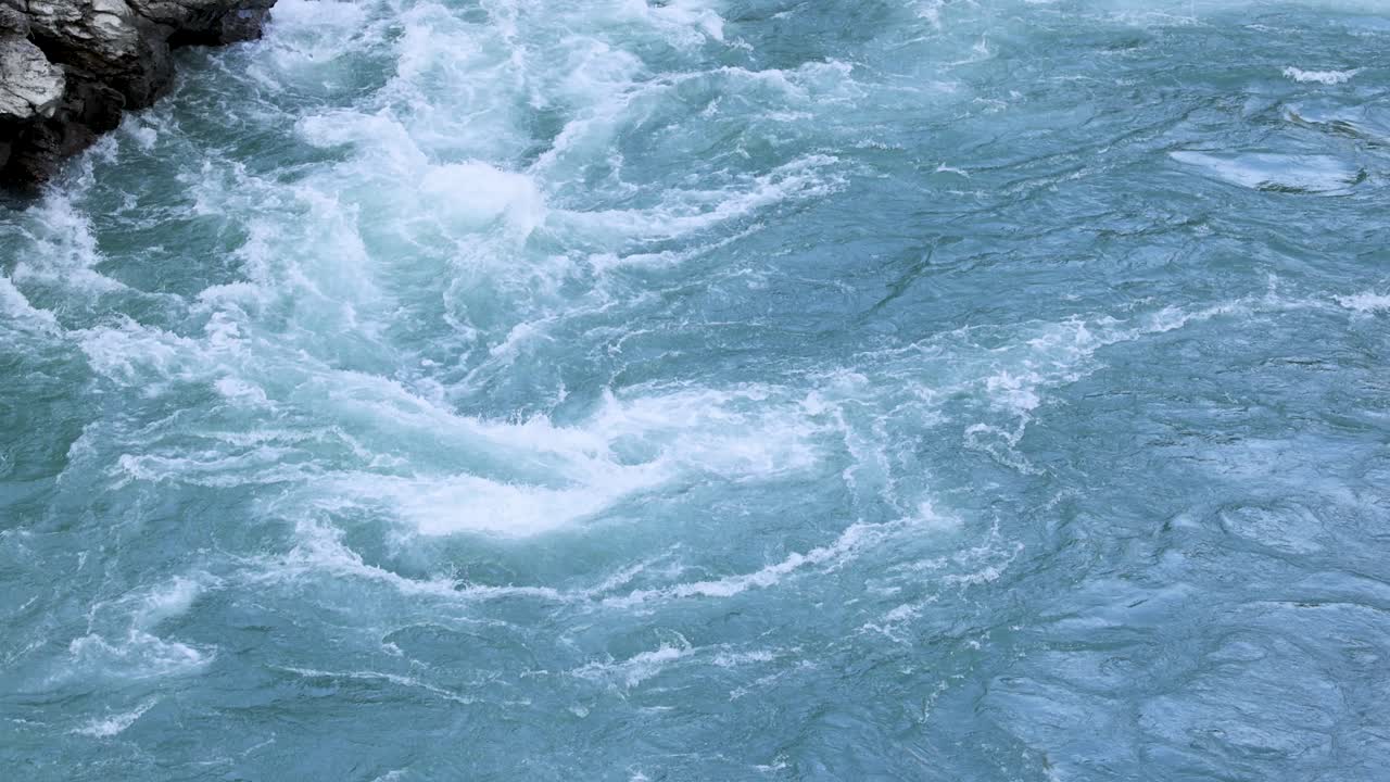 Dynamic river rapids flow through rocky cliffs, showcasing powerful water movement and natural beauty in Queenstown, New Zealand