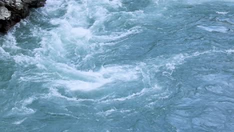 dynamic river rapids flow through rocky cliffs, showcasing powerful water movement and natural beauty in queenstown, new zealand