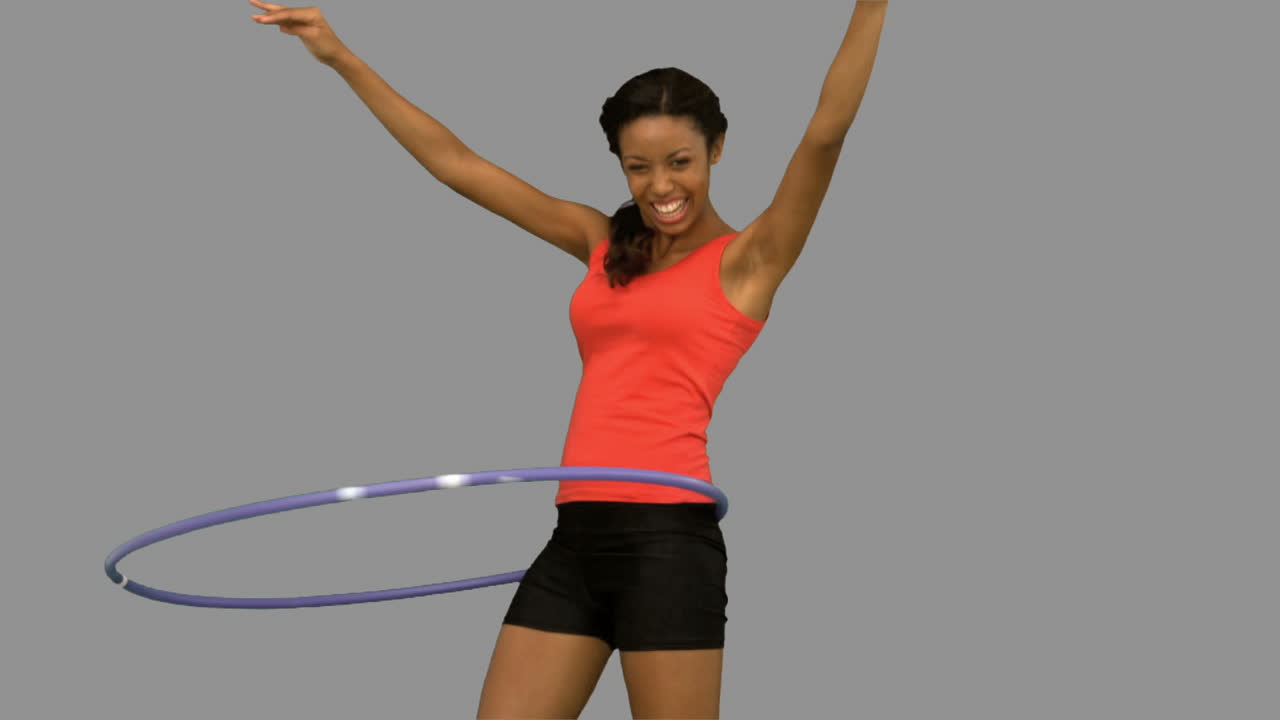 Woman playing with a hula hoop on grey screen