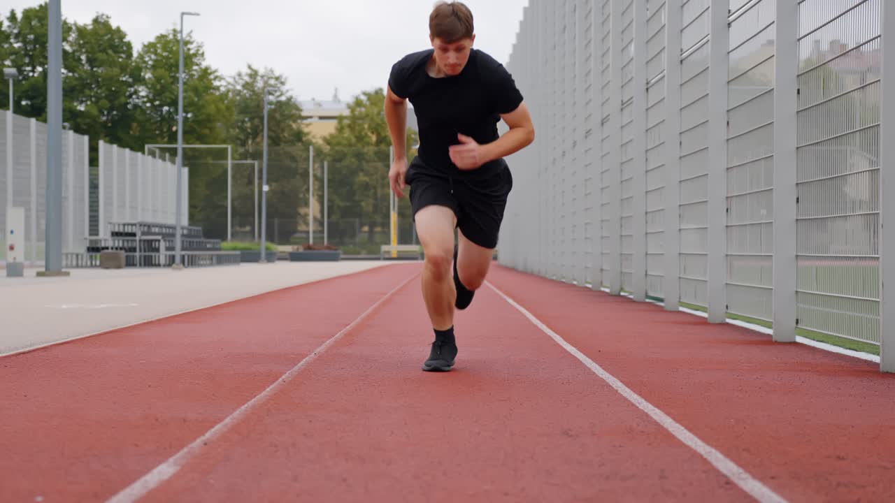 Athletic male in outdoor park prepares for sprint, launching forward with energy towards the camera