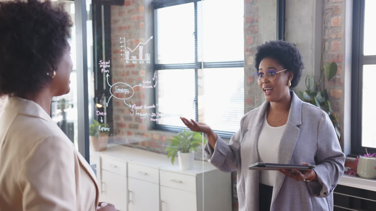 Presenting business strategy, woman holding tablet and discussing with colleague