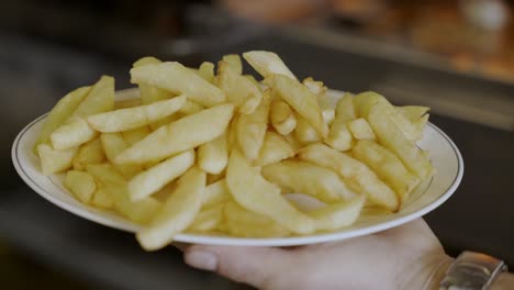 person holding french fries plate ready to be served for customers