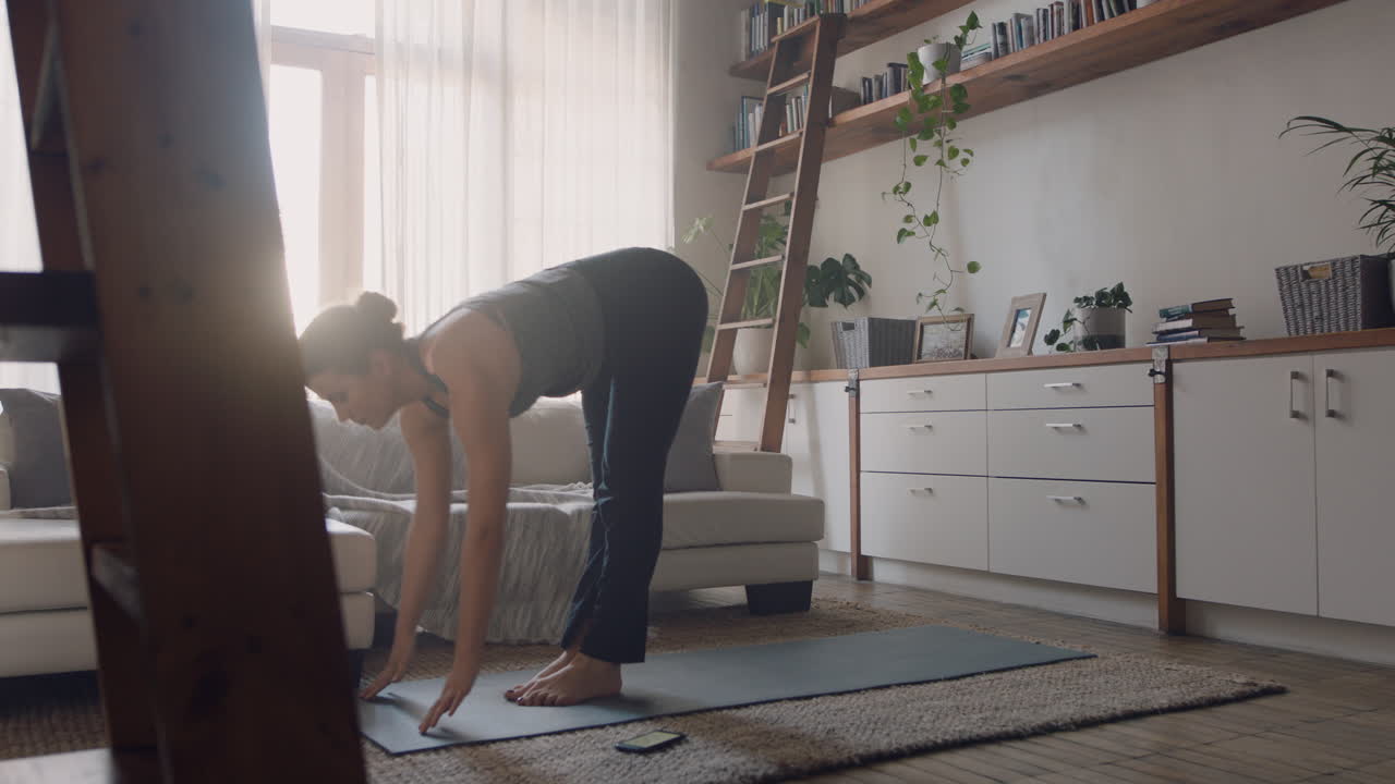 집에서 운동하는 건강한 요가 여성은 아침 피트니스 운동을 즐기며 거실에서 앞으로 굽히는 포즈를 연습합니다