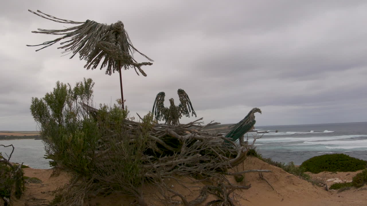 representación artística abstracta de un águila con las alas extendidas, posada en un nido y con vistas a una playa