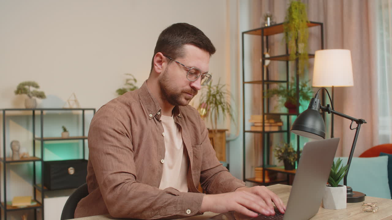 Happy caucasian young businessman closing laptop after finishing work relaxing at home office desk