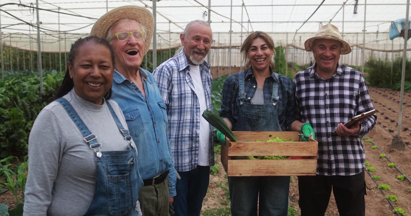 Smiling Diverse Farmers Team in Greenhouse with Freshly Harvested Vegetables