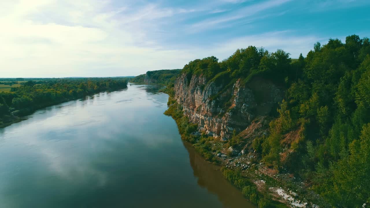 Sera nella natura selvaggia. La fitta foresta cresce su una roccia inaccessibile. Il cielo blu si riflette sulla superficie dell'acqua del fiume. Un luogo per la solitudine e il relax.