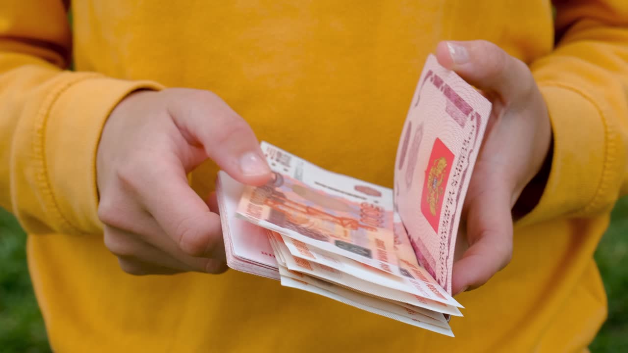 Employee received salary in cash and put money in passport. Saved up some Russian rubles. 4K slow motion footage. Woman puts paper five thousand ruble bills in foreign passport of Russian Federation.