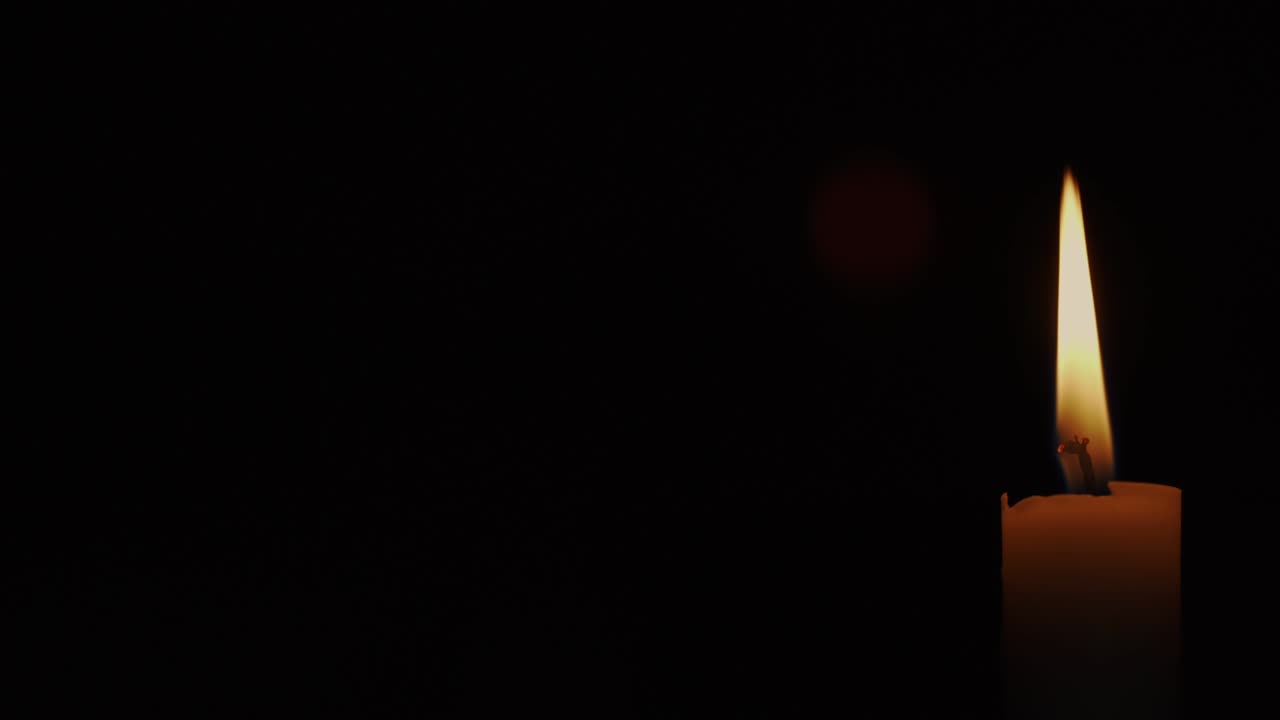 yellow candle with bright flame moving on dark background