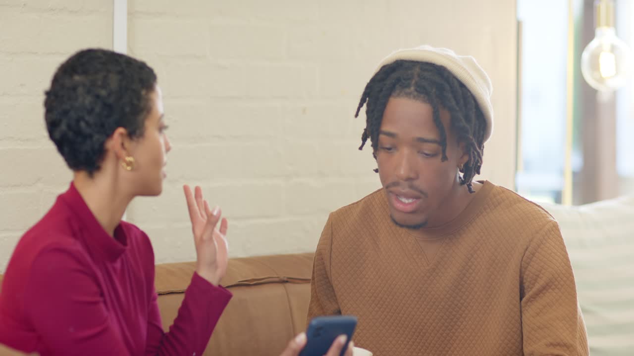 Amigos diversos batendo papo ao compartilhar a tela do celular e analisá-la no sofá com caneca e smartwatch