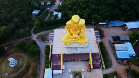 4k aerial top down view of luang pu thuat golden statue at dawn