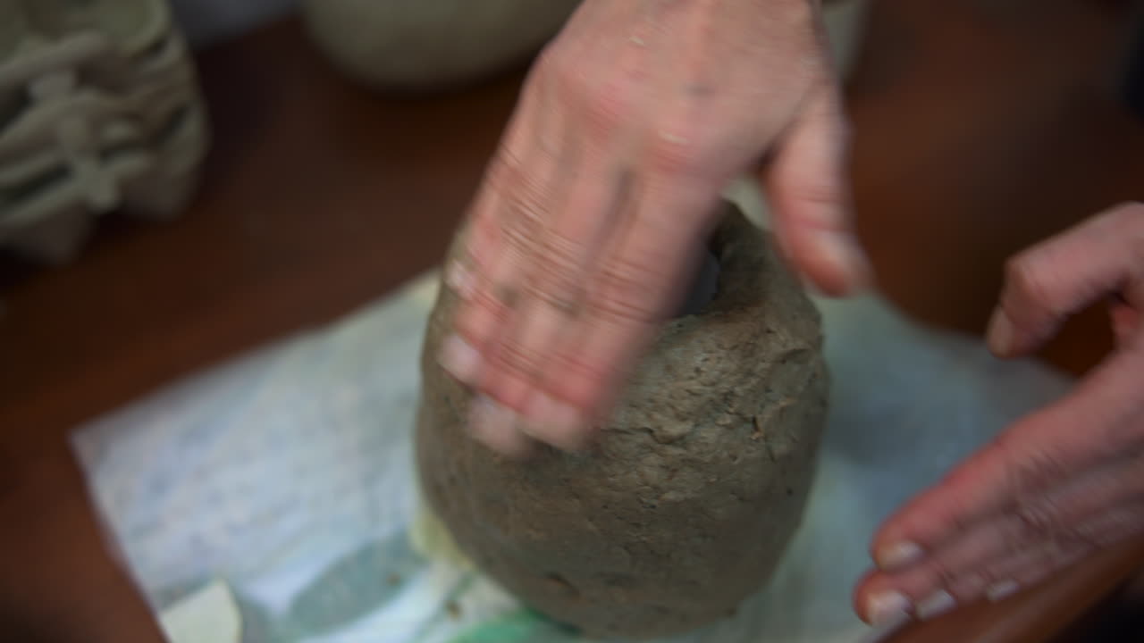 Mani caucasiche che rifiniscono un portacandele con cavità centrale, levigando la superficie esterna per una texture uniforme, primo piano.