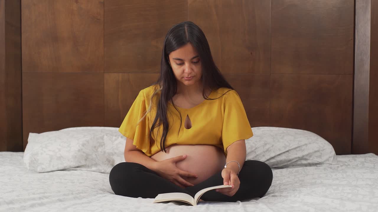 책을 읽고 침대에 앉아 젊은 라틴 여자