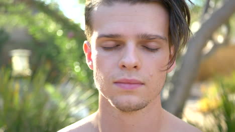 a fit young attractive white man looking serious while exhaling and breathing deeply during a reflective meditation session focusing on his life and the meaning of existence