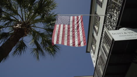 Amerikanische-Flagge-Weht-In-Der-Nähe-Von-Palmen-In-Der-Innenstadt-Von-Charleston,-South-Carolina,-Schieber