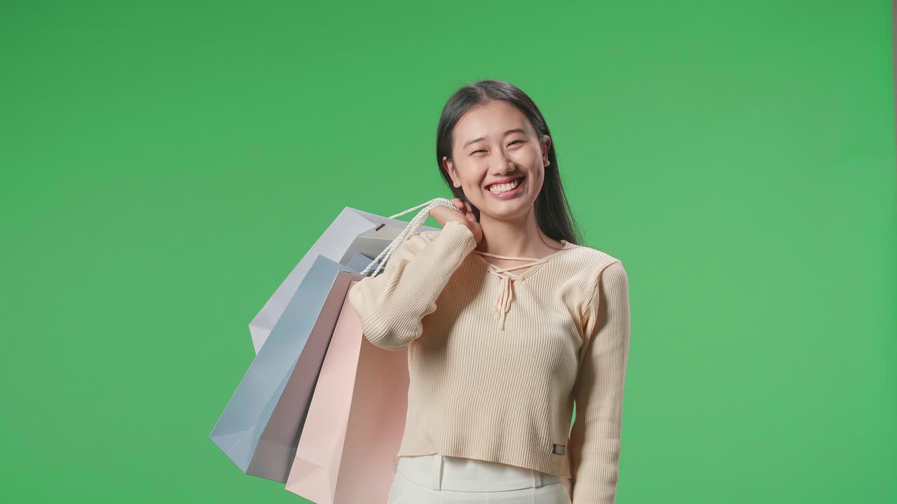 An Asian Shopping Woman Holding Shopping Bags Up Being Happy And Smiling To Camera While Standing In Front Of Green Screen