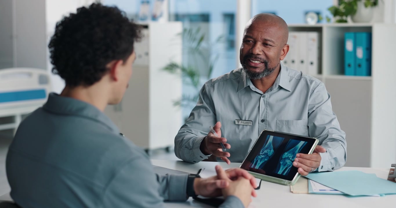 Doctor Explaining Knee X-ray Results to Patient on Tablet