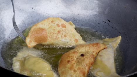 cook flipping empanadas and cooking them until golden and crispy