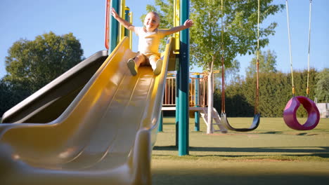 happy young boy sliding down a playground slide