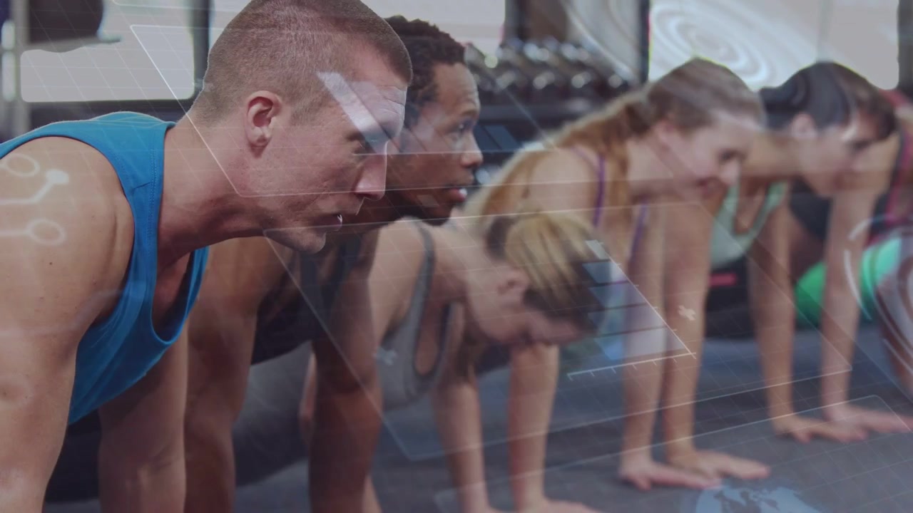 Front-left man in blue tank guiding group performing gym push-ups on mats, coach cue driving pace