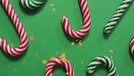 animation of christmas stars falling over christmas candies on green background