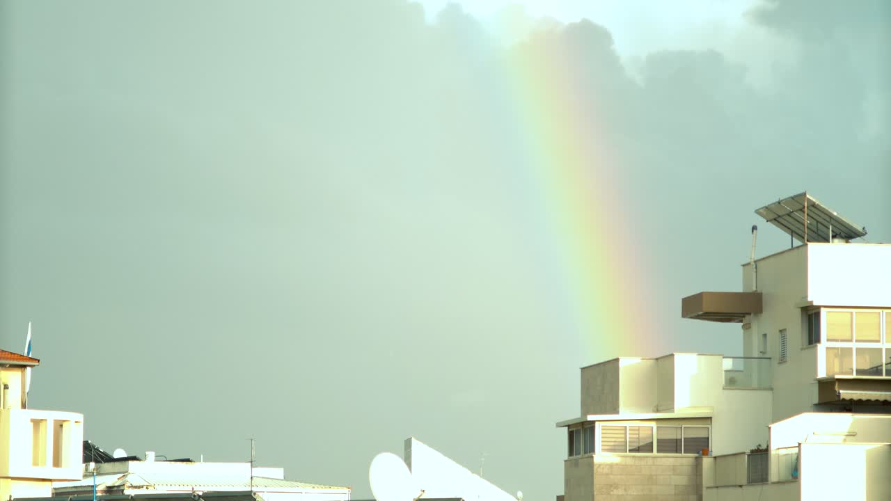 un dramático lapso de tiempo de un arco iris en movimiento luces sobre los edificios de la ciudad de israel, nubes deslizantes, cielo azul oscuro, luz del sol en los techos, clima lluvioso, oriente medio tel aviv, sony 4k video