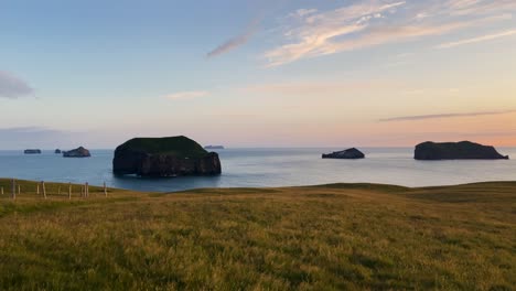 paisaje marítimo de la hora dorada con océano sereno y fondo césped en islandia, islas lejanas, estado de ánimo tranquilo