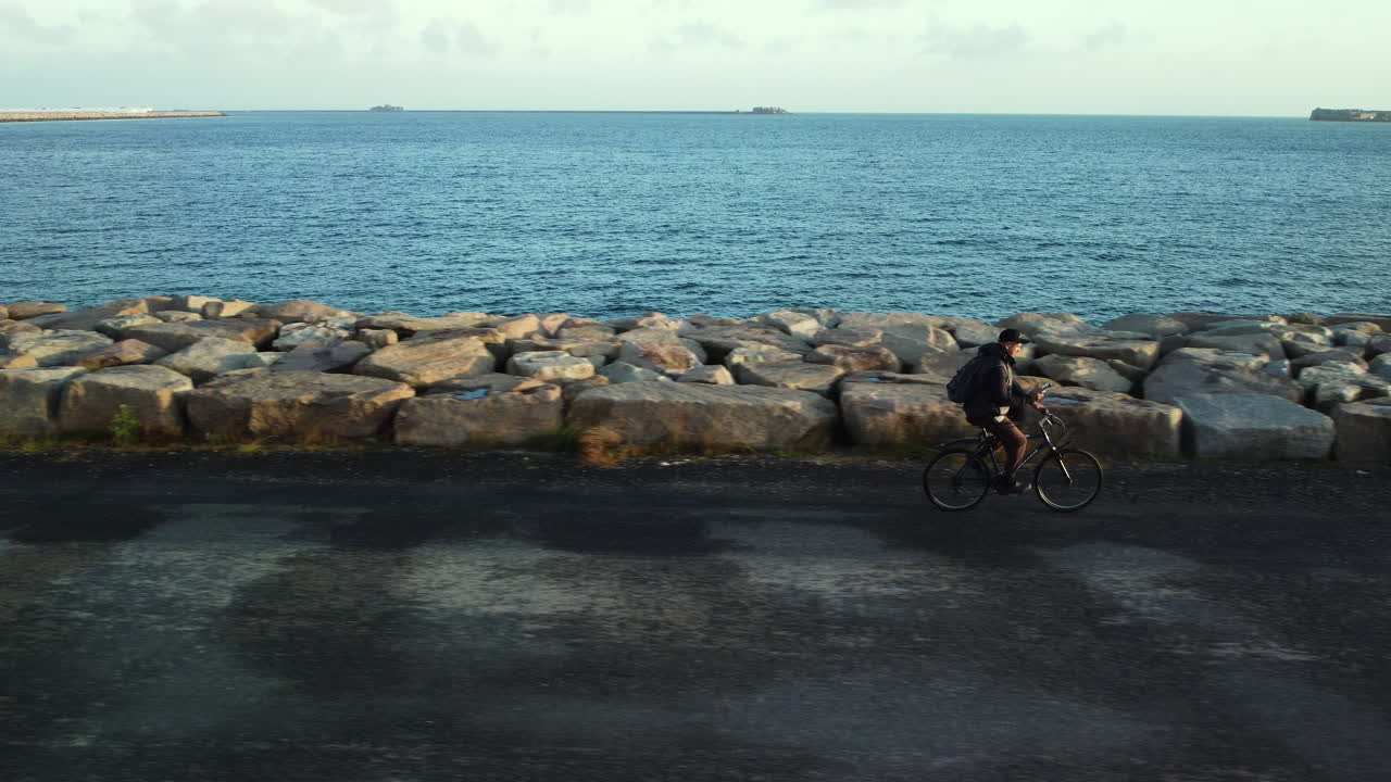 Man Cycling Along a Coastal Pier