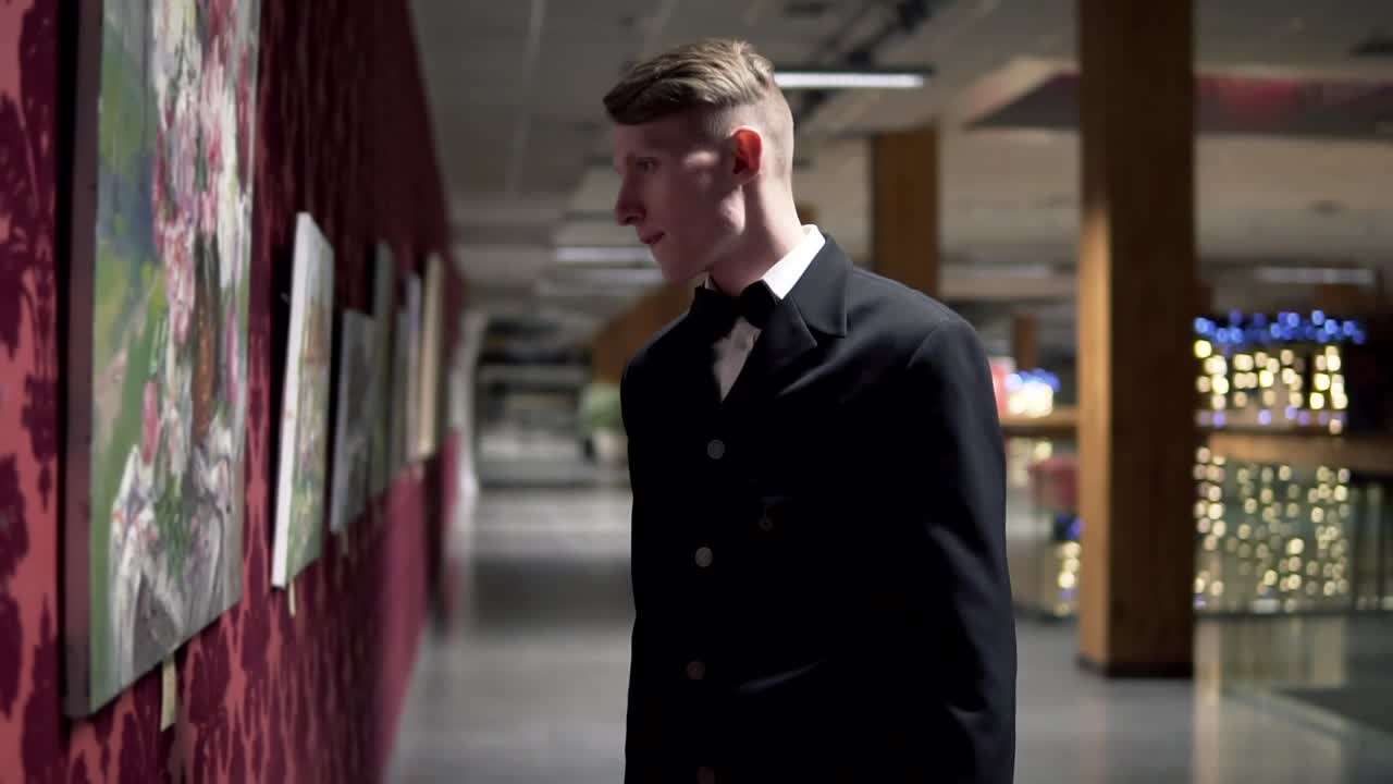 예술 갤러리의 그림을 조심스럽게 바라보는 젊은 사업가