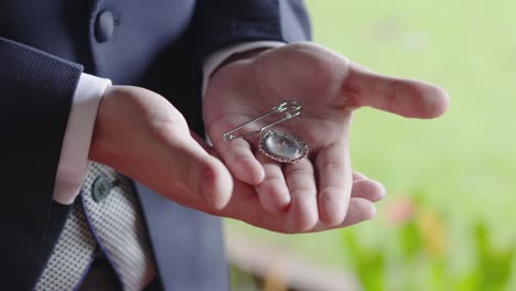 close-up of man holding a locket with a photograph in his hands during his wedding ceremony