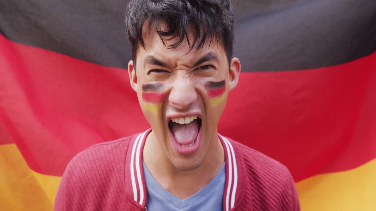 retrato de un feliz hombre biracial con la bandera de alemania en el fondo y en la mejilla