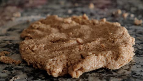 Handheld-close-up-of-stretched-whole-wheat-cookie-dough-on-countertop